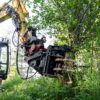 JAK-250R energiakoura joukkokeräimellä kiinnitettynä kaivinkoneeseen, leikkaamassa puita tehokkaasti.